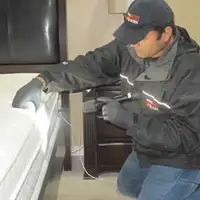 Bed bug inspection technician checking a mattress and bed frame for signs of infestation in New Haven, CT