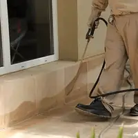 General pest control technician spraying exterior perimeter around a home in New Haven, CT