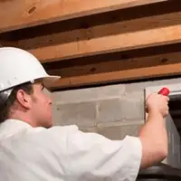 Termite inspection technician checking a basement wall and framing for termite activity in New Haven, CT